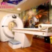 Modern CT scan room at Health Quest Imaging & Diagnostics featuring a state-of-the-art CT scanner, patient table, wooden flooring, and artistic wall mural for a comfortable diagnostic environment.